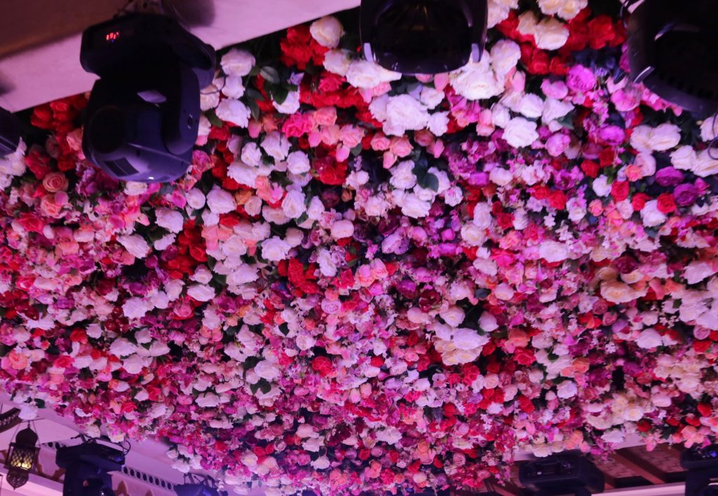 A wedding hall ceiling adorned with colorful flowers and twinkling lights, showcasing budget-friendly decoration ideas.