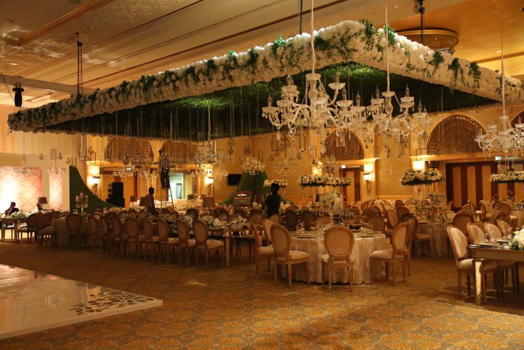 Elegant banquet room in Dubai featuring chandeliers and tables, showcasing luxurious flower arrangements for VIP guests.