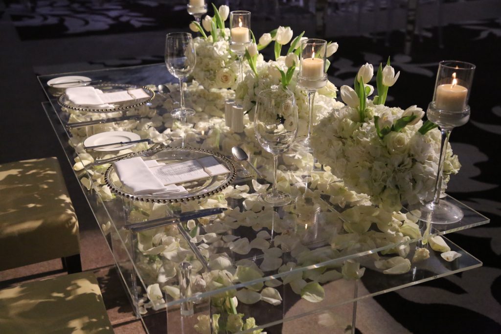 A beautifully arranged table featuring white flowers and candles, set for a wedding by celebrity florists in Dubai.