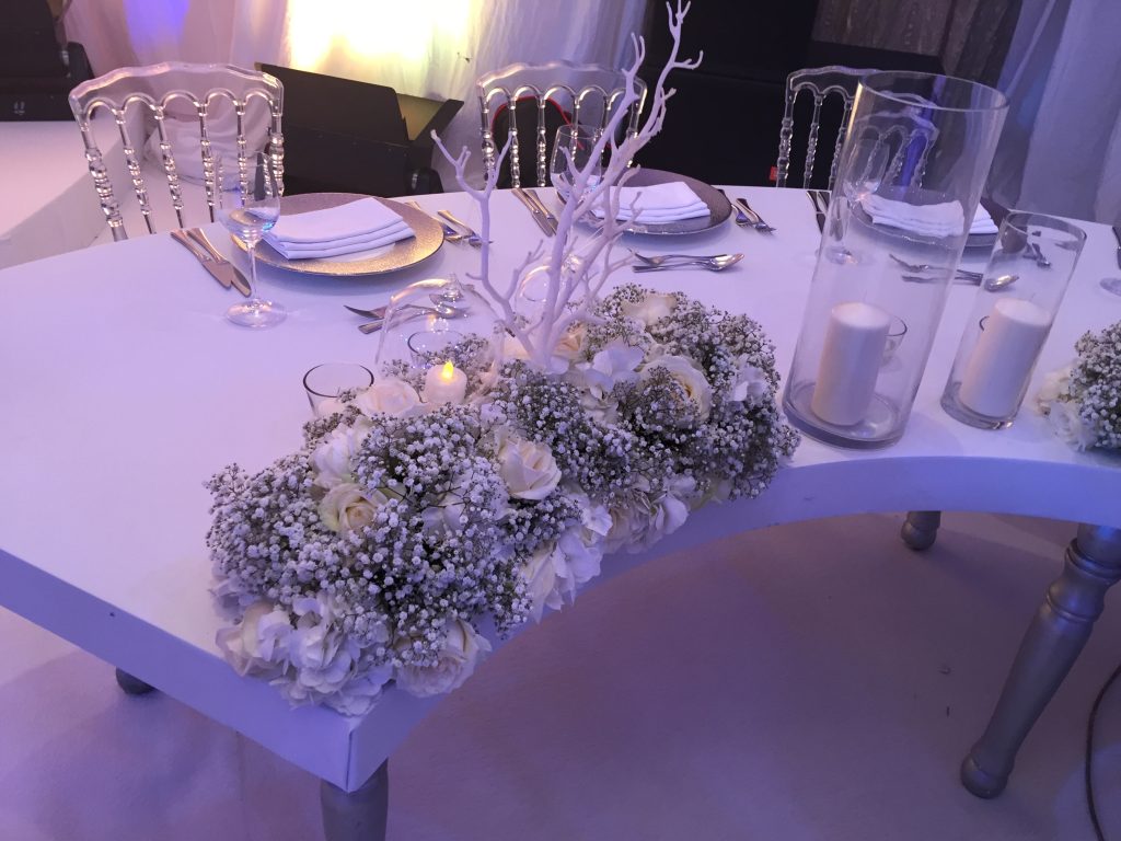 A beautifully arranged table with white flowers and candles, perfect for a New Year’s Eve party setting.