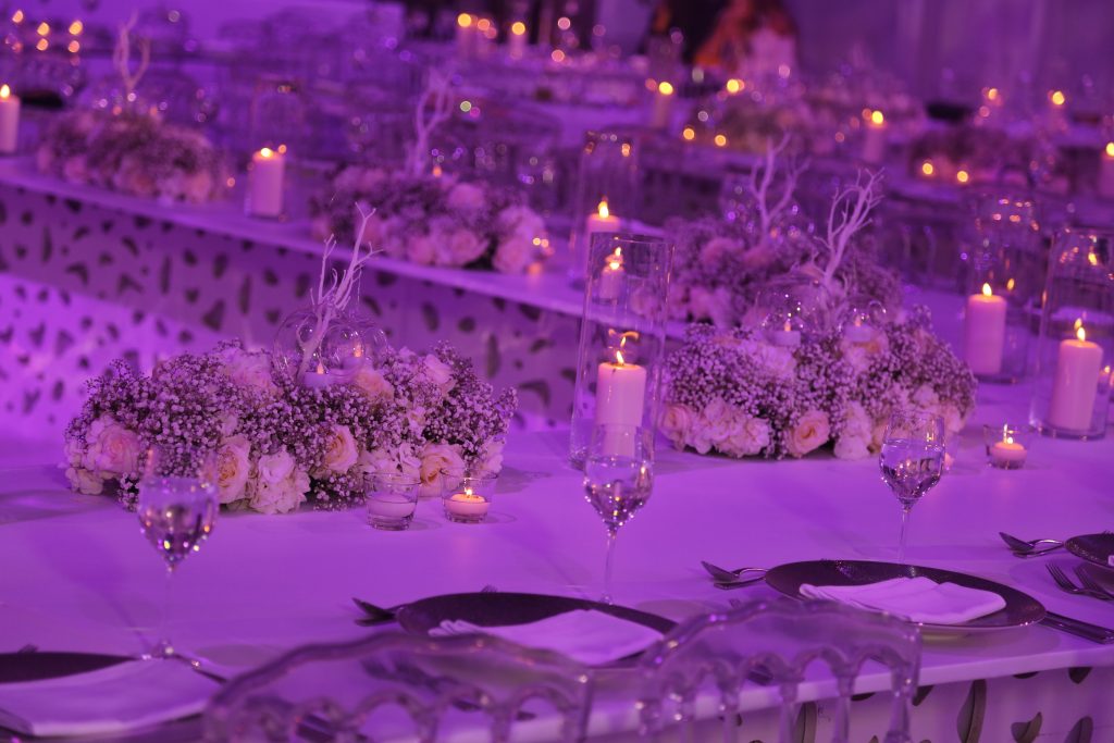 A table adorned with purple lighting and flickering candles, creating an elegant and inviting atmosphere.