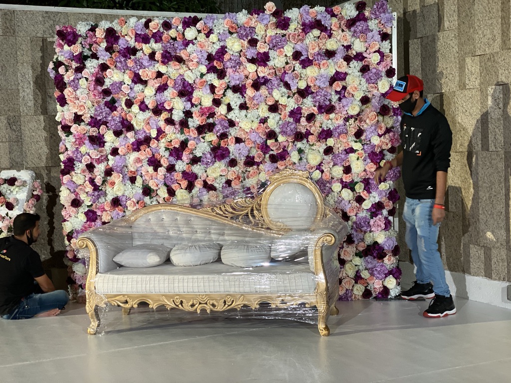A man arranging flowers on a wall, demonstrating a custom design setup for an event with a florist.