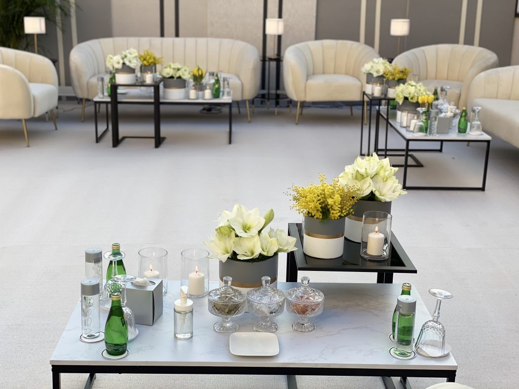 A bright white room featuring white couches and tables, designed for DIY flower centerpieces at small events.