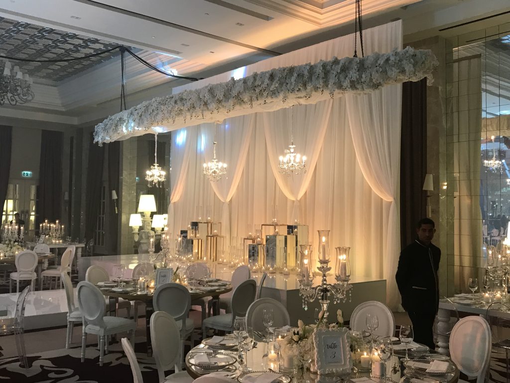 A wedding reception featuring elegant white and gold decor, showcasing VIP event flower arrangements throughout the venue.