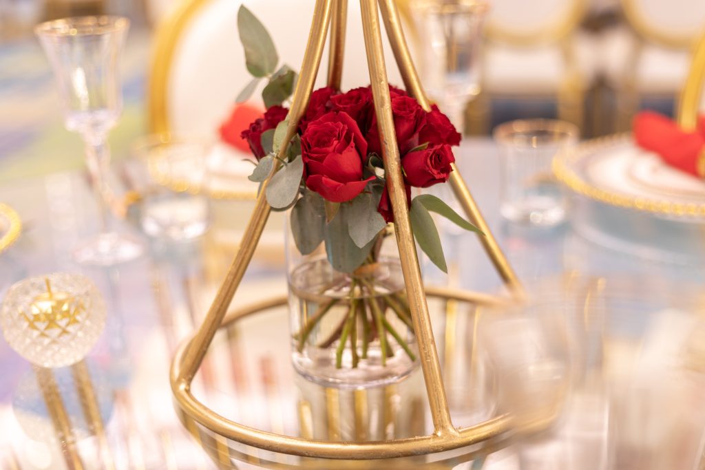 A romantic gold and red table setting featuring a vase of red roses, perfect for Valentine's Day decor.