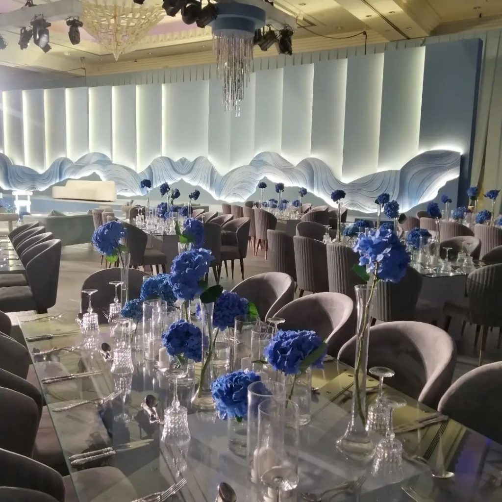 A banquet room featuring blue flowers and white tablecloths, showcasing minimalist Scandinavian decor for weddings.