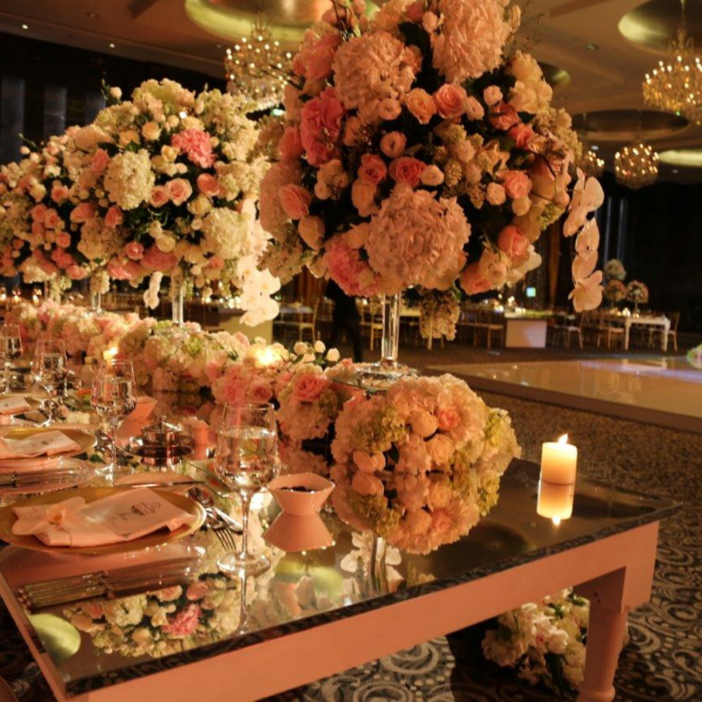 A beautifully set long table featuring vibrant flowers and flickering candles, enhancing the ambiance for a special occasion.