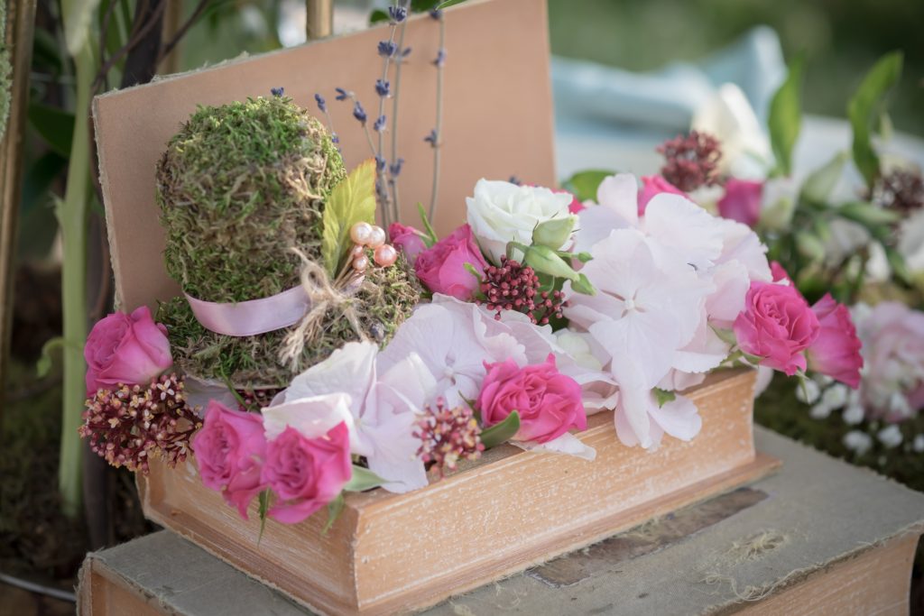 A decorative box adorned with colorful flowers and green moss on its surface.